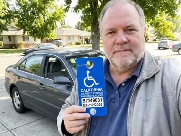 Man hanging a California disability placard from his rearview mirror