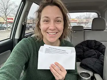 Karen M. from Ohio smiling in her car holding documents